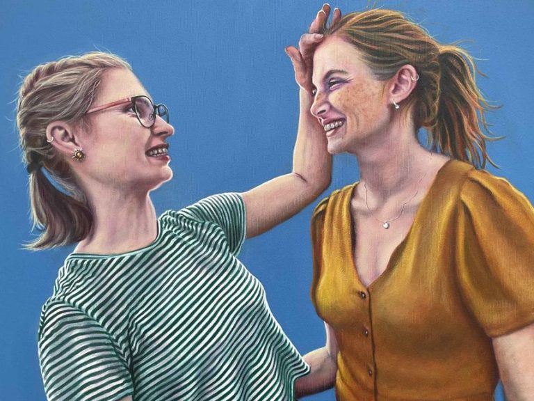 Soulmates 1, Öl auf Leinwand Ölporträt: Zwei Frauen lachen und interagieren fröhlich vor einem einfarbigen blauen Hintergrund.